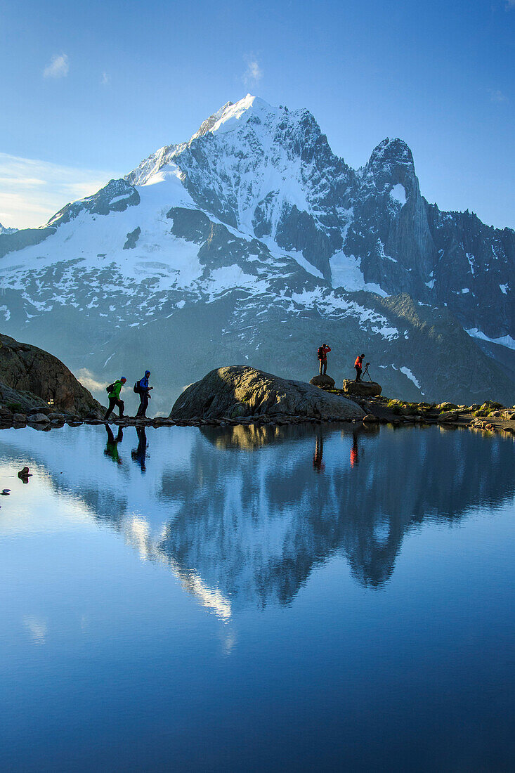 Hikers on the shores of Lac de Cheserys, with Aiguille Verte reflected at dawn, Chamonix, Haute Savoie, French Alps, France, Europe