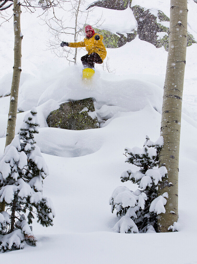 A man wearing a yellow jacket snowboards through powder snow at Brighton Resort.