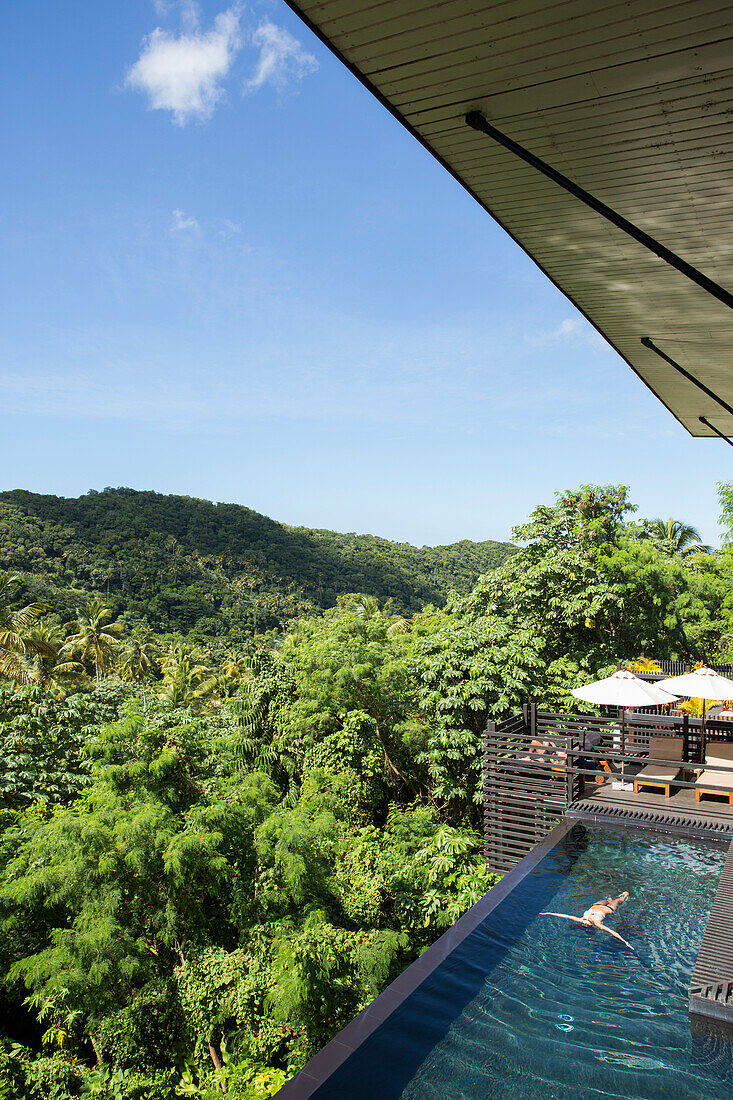 Woman relaxes in an infiinty pool in Saint Lucia overlooking the jungle