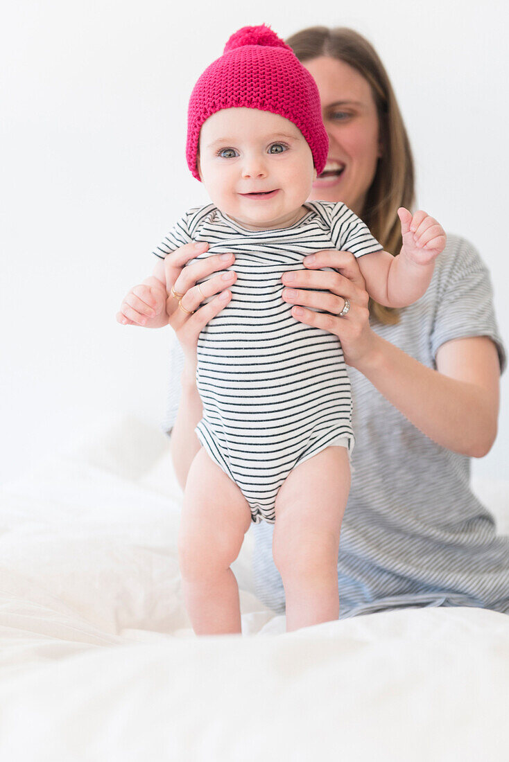 Caucasian mother holding baby daughter on bed