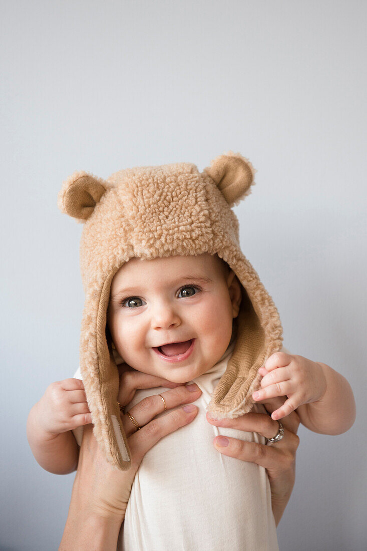 Caucasian mother holding baby daughter in fuzzy hat