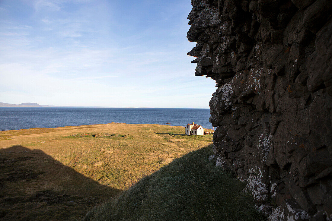 Rocky cliff over rural field and seascape