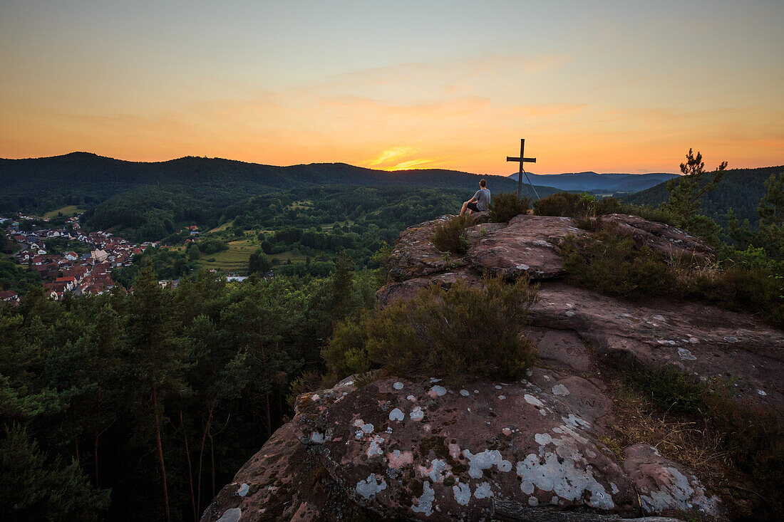 Hiker enjoying sunset upon Hockerstein, Palatinate Forest, Rhineland-Palatinate, Germany