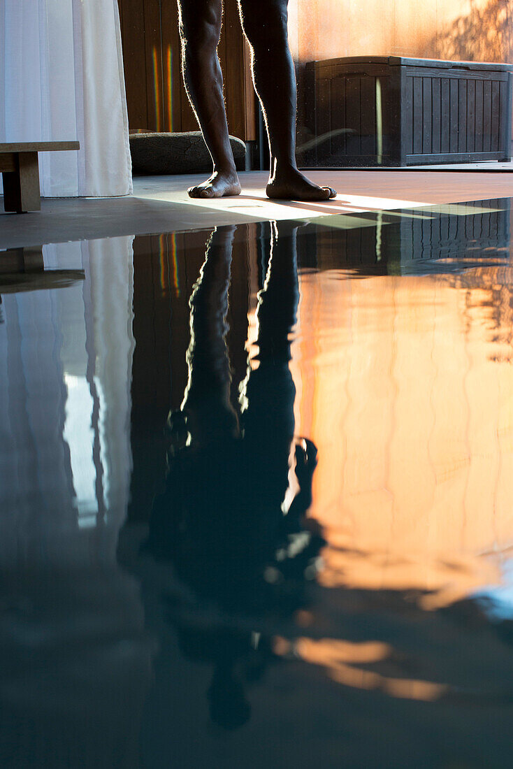Man's reflection on spa swimming pool, low section