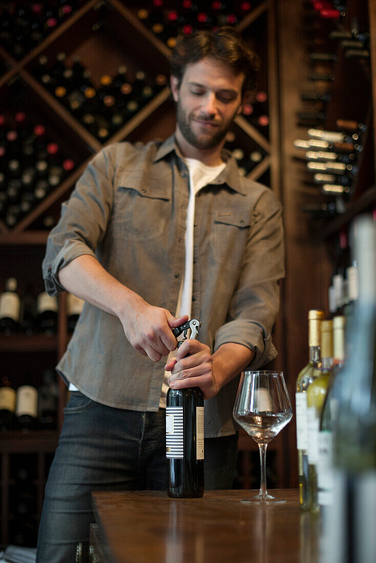 Sommelier uncorking bottle of wine