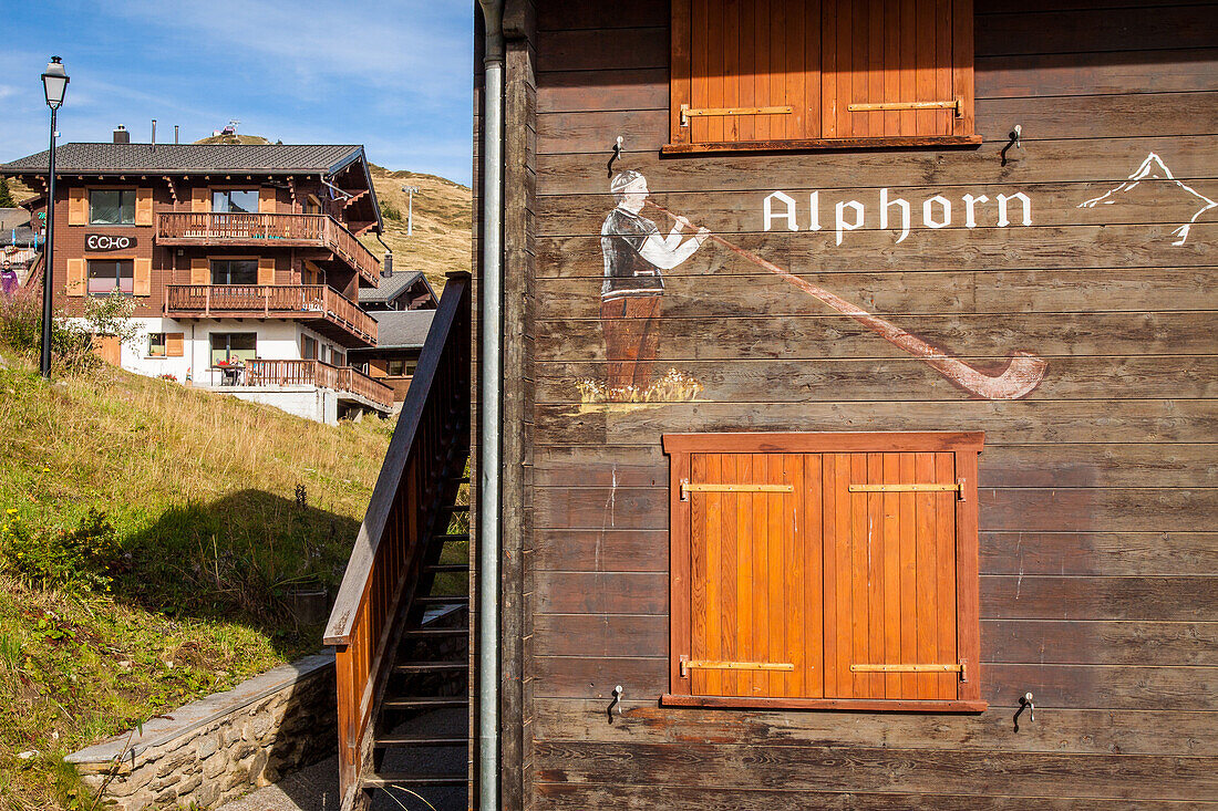 dessin d'un homme jouant du cor des alpes sur la facade d'un chalet en bois typique dans le centre du village de bettmeralp, station de ski, bettmeralp, canton du valais, suisse