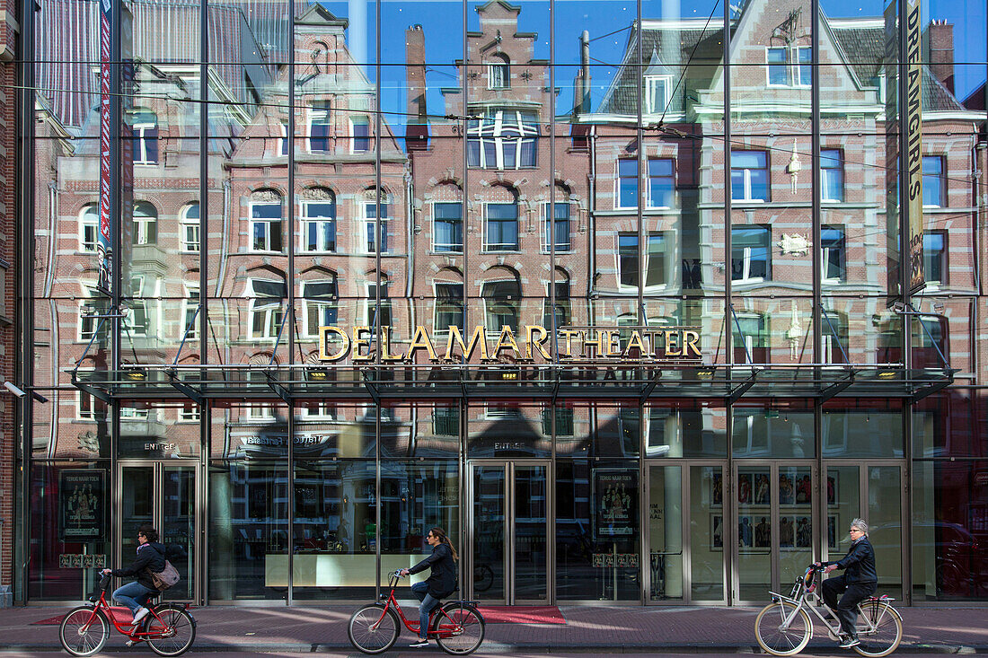 bike riding and reflections of buildings, contrast between old and modern in front of the delamar theater, marnixstraat, amsterdam, holland