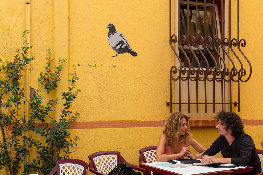 mural with a pigeon and the quote 'god will reward you' on the terrace of a cafe, cerbere, (66) pyrenees orientales, languedoc roussillon, france