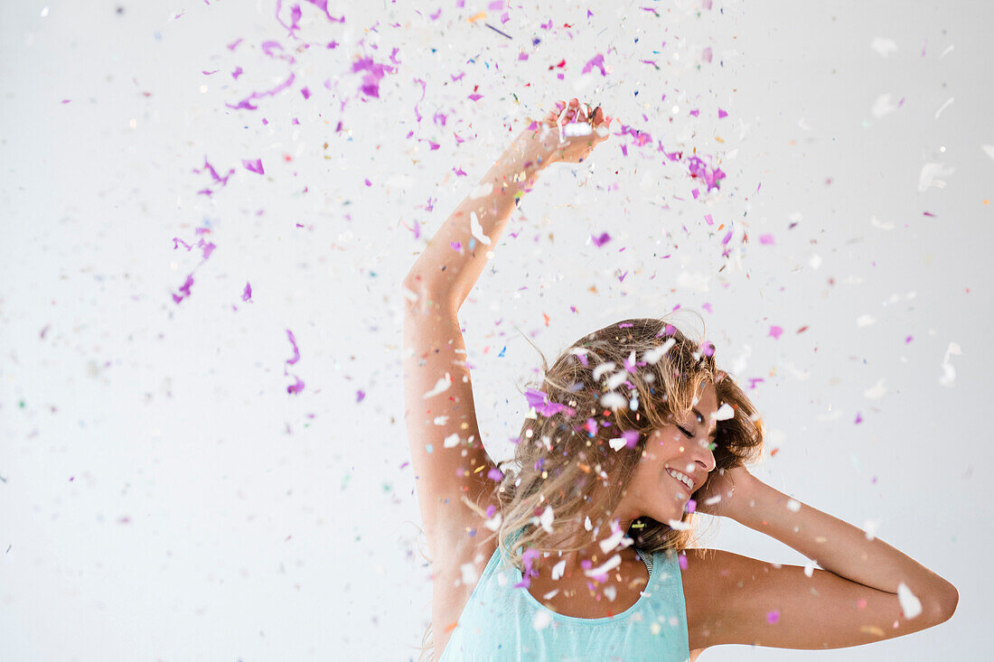 Mixed race woman playing in confetti