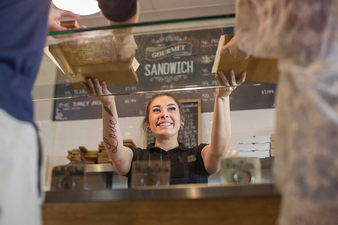 Server handing pizza to customers in cafe