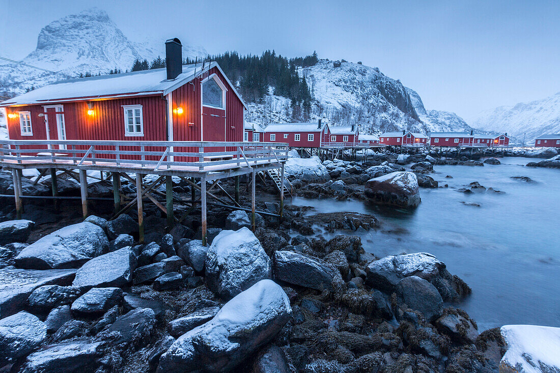 Typical fishermen houses called rorbu in the snowy landscape at dusk, Nusfjord, Nordland County, Lofoten Islands, Norway, Scandinavia, Europe