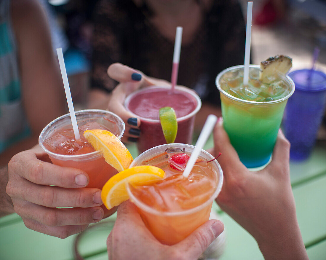 Cropped image of people holding drinks outdoors