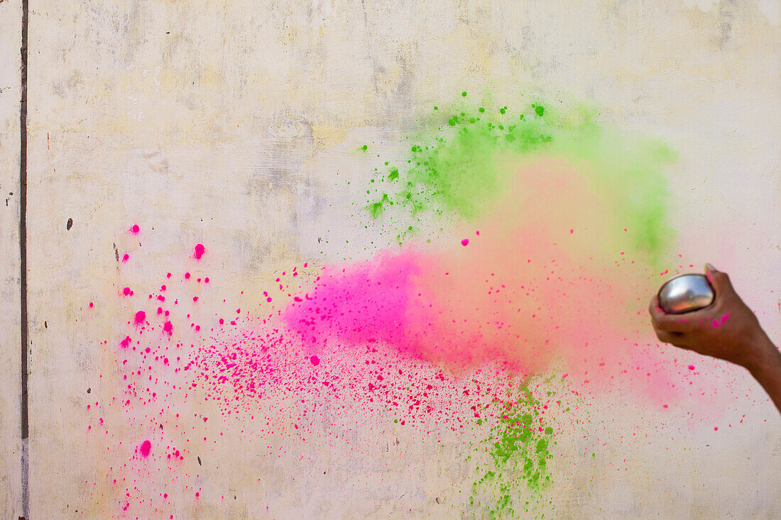 Cropped image of hand throwing powder paints on wall during Holi