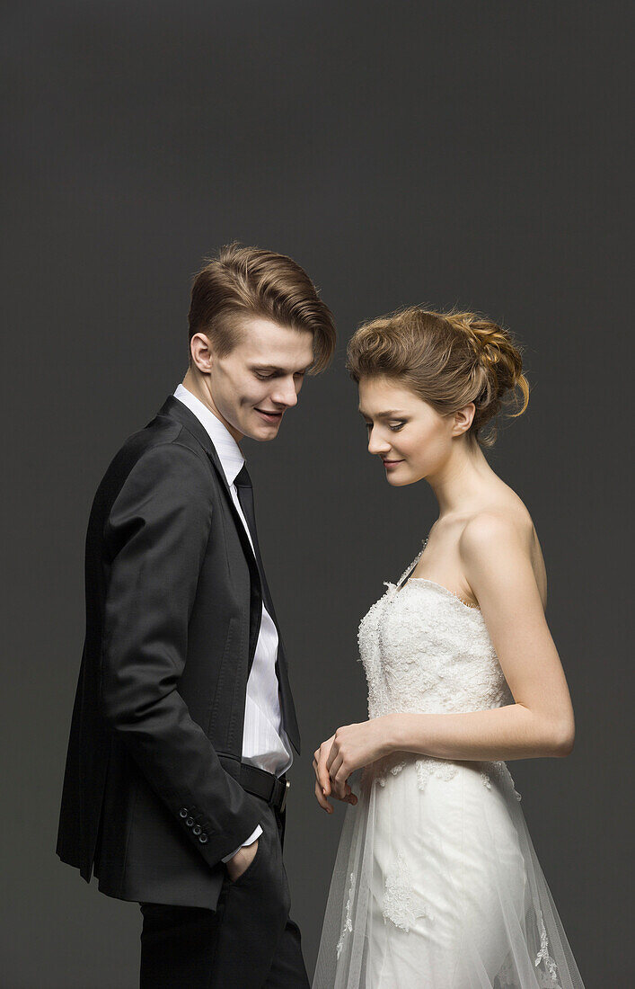 Side view of newly wed couple over gray background