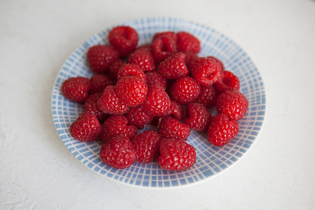 Raspberries in plate on white background