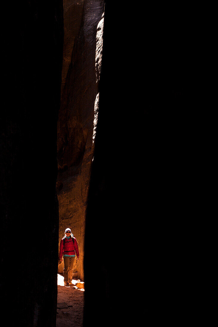 A woman hikes through a slot canyon in the Chesler Park are of Canyonlands National Park near Moab, Utah.