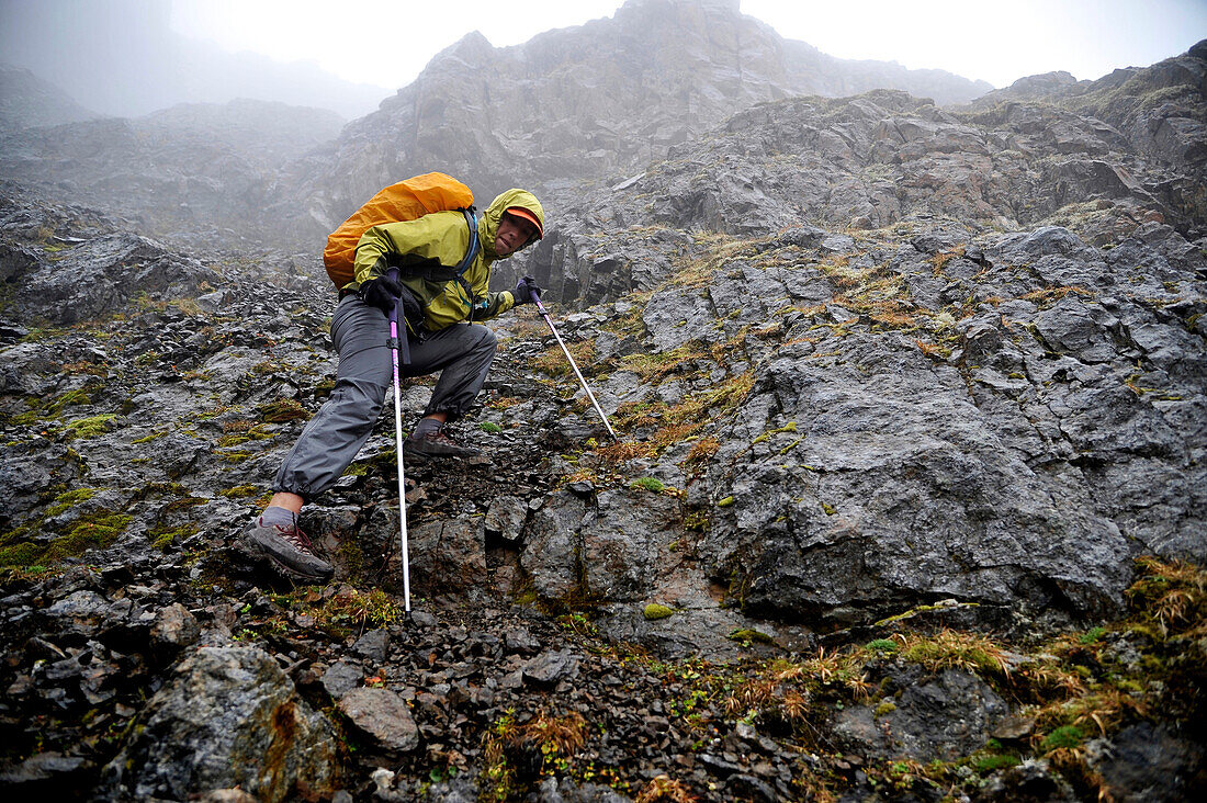 Female hiker descends a steep gully off North Suicide Peak toward Rabbit Lake in the front range of the Chugach Mountains in Anchorage, Alaska August 2011.