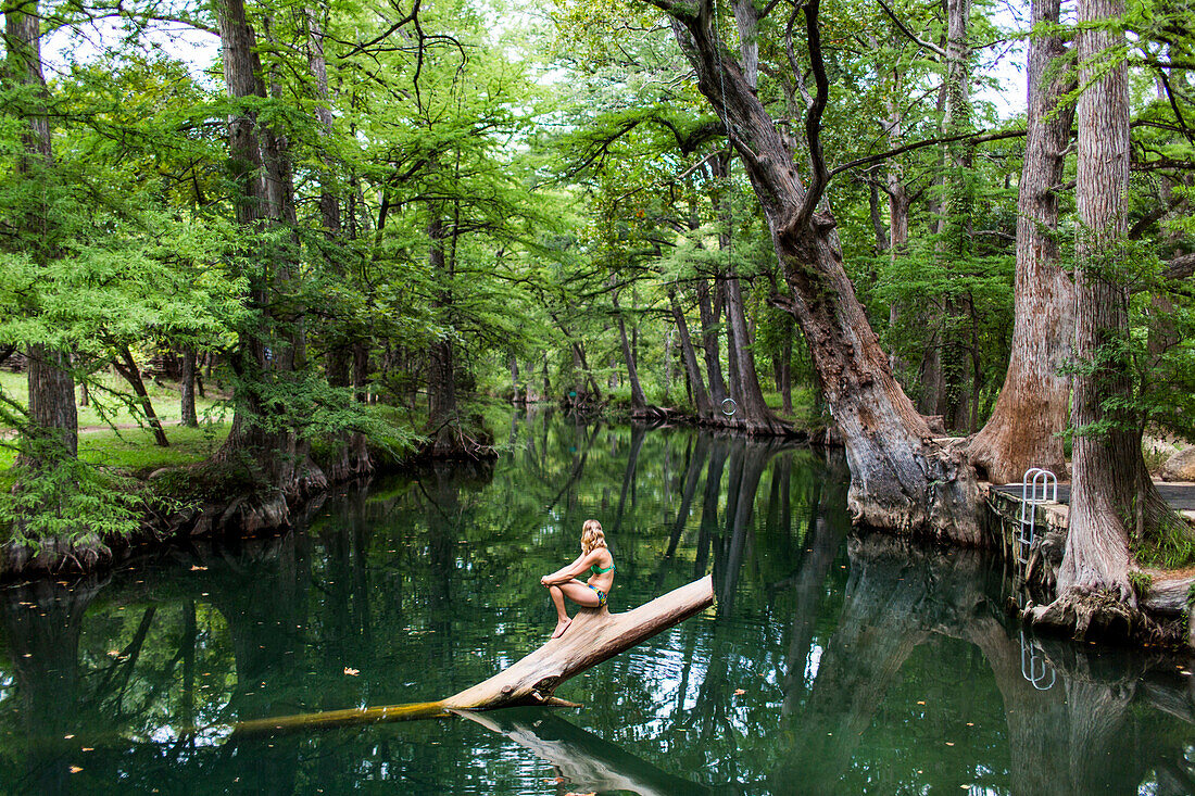 A young woman enjoys a calm swimming hole, the Blue Hole, near Wimberley, Texas.