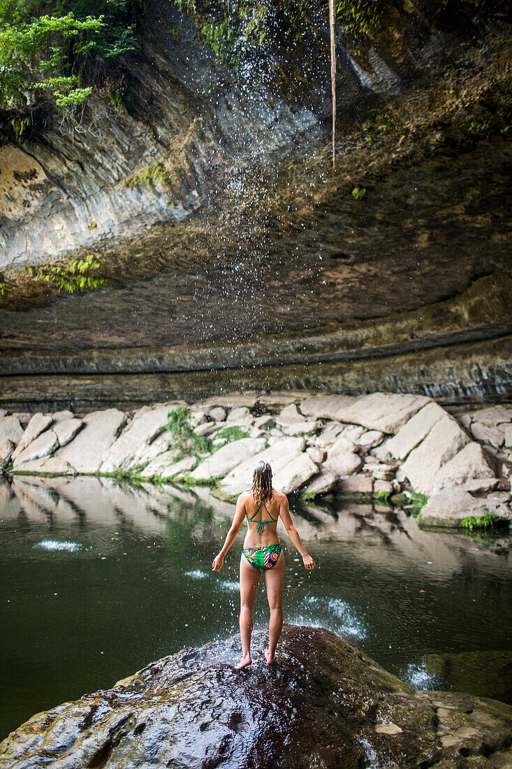 A young woman enjoys the Hamilton Pool near Wimberley, Texas on a hot day.