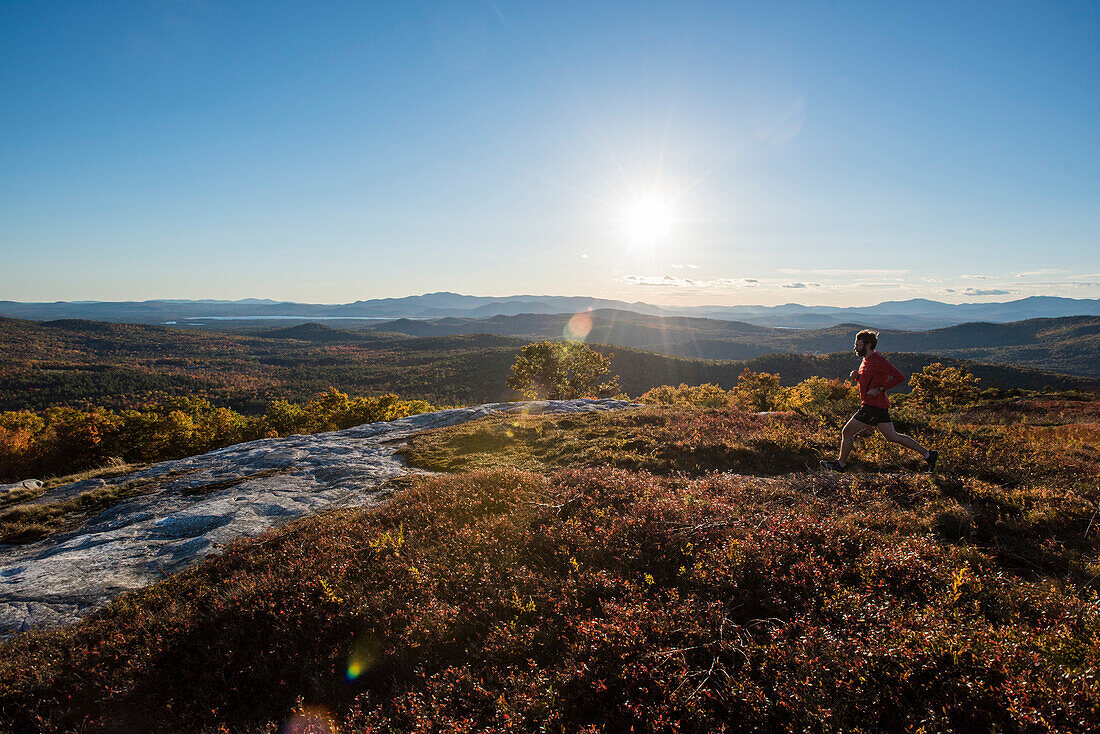 Trail running along the summit of Foss Mt. with the setting sun and White Mountains in the background.