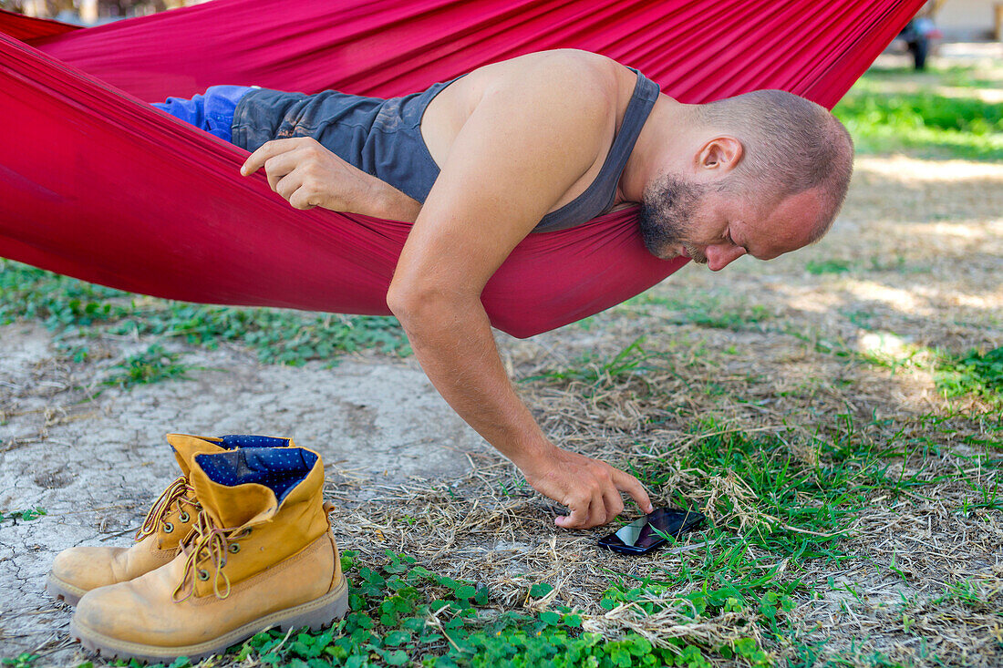 Young man using mobile phone  in a hammock