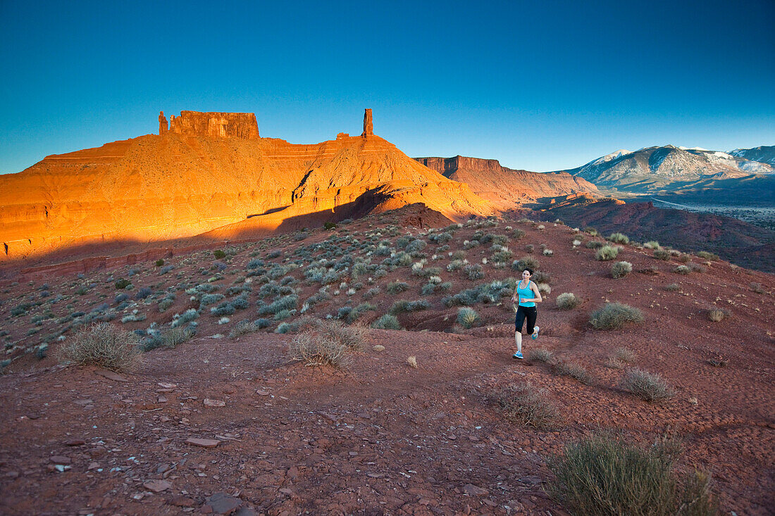 Sarah Hedden running with Castleton Tower in the background, Castle Valley, Utah.