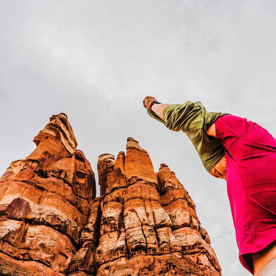 Low angle view of woman with her hands overhead, taking off her shirt among unusual sandstone formations in the Canyonlands National Park.