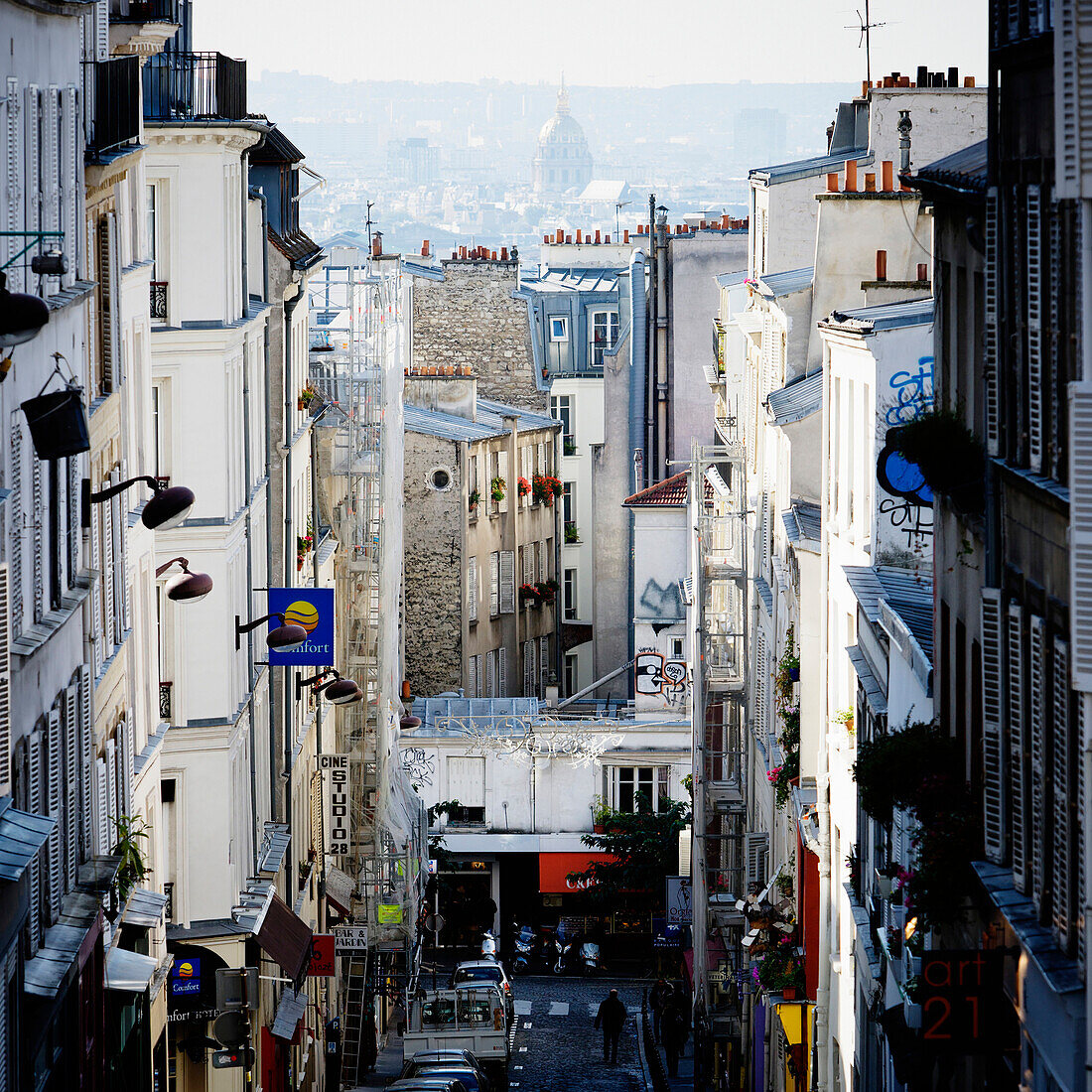 Looking down from the only hill of Paris, through a narrow Parisian street in the Montmartre, is the Paris cityscape.