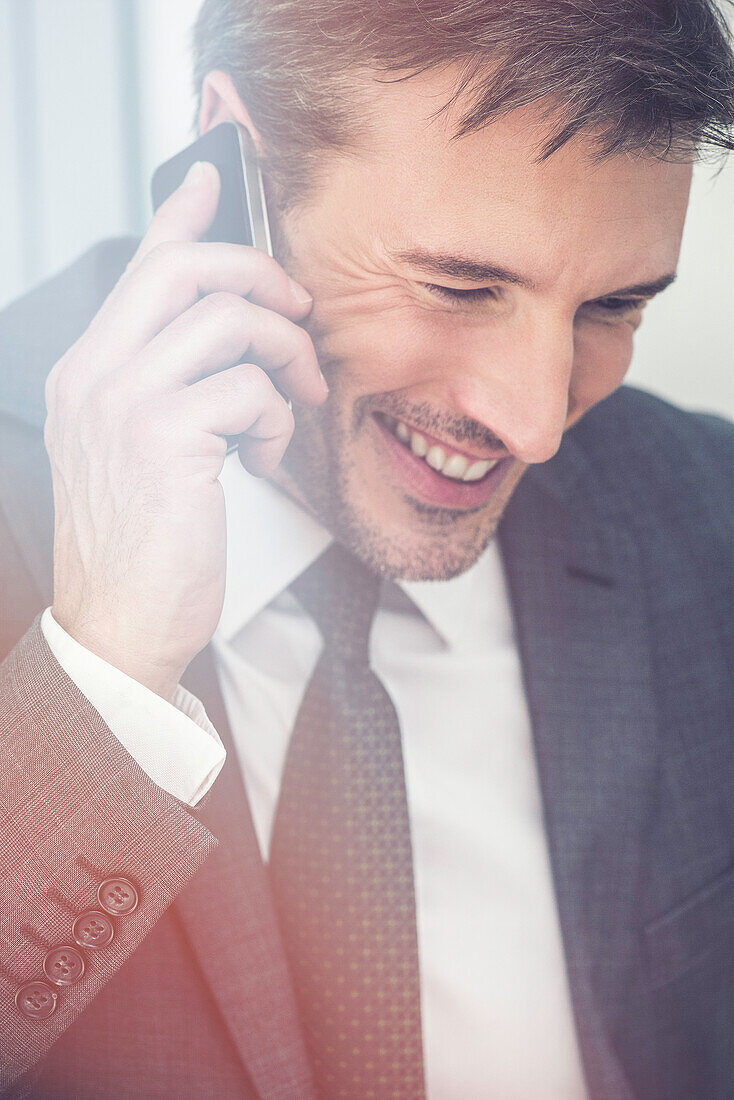 Businessman talking on cell phone, smiling