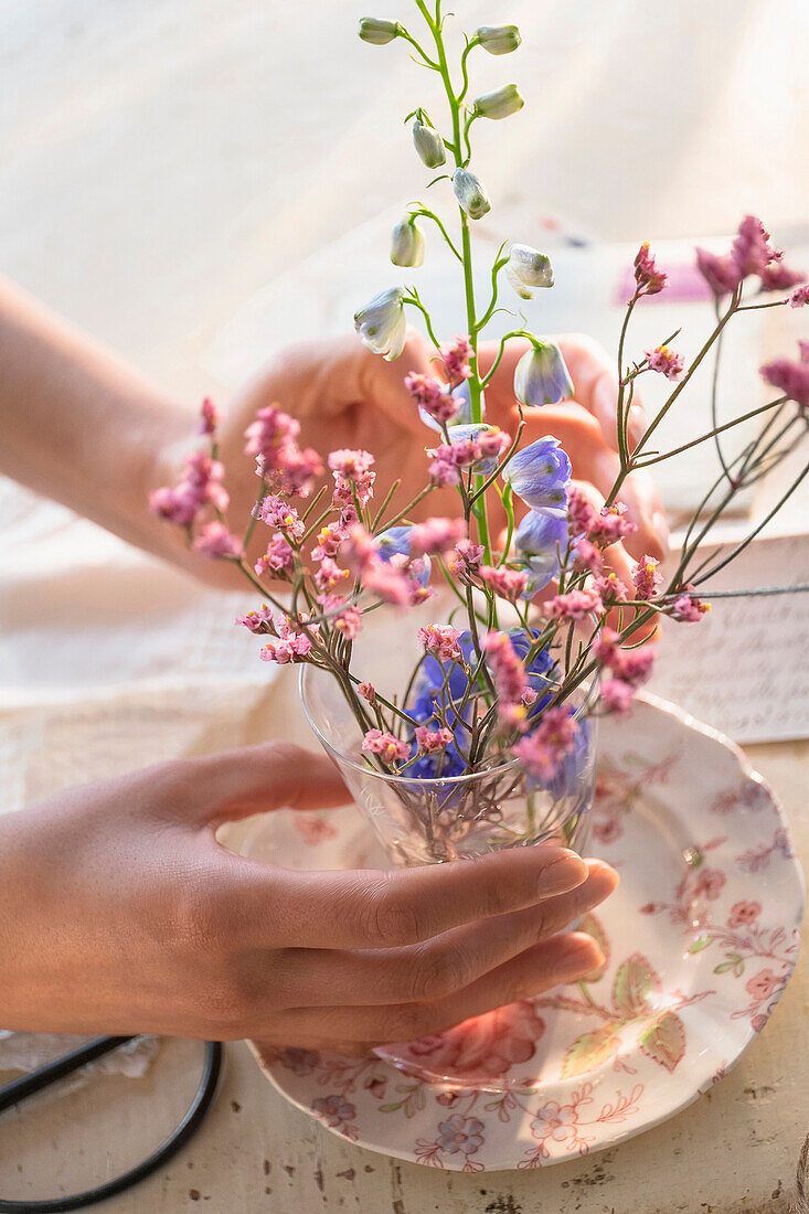 Hispanische Frau arrangiert Blumen in einer Glastasse