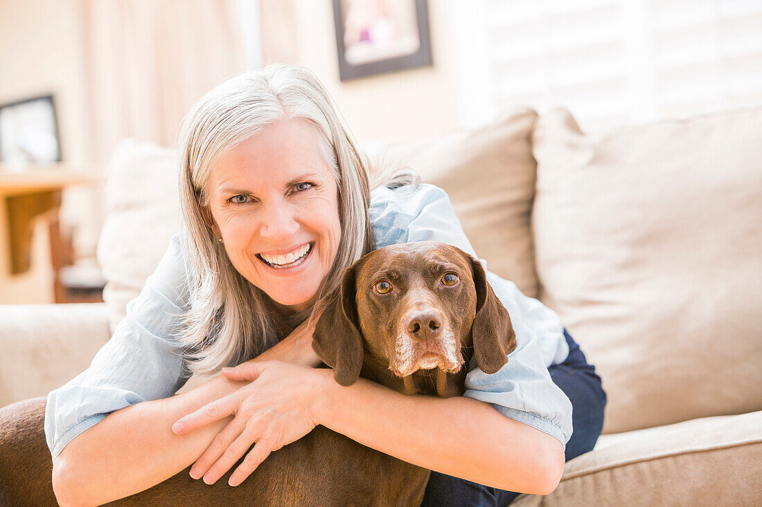 Caucasian woman hugging dog on sofa