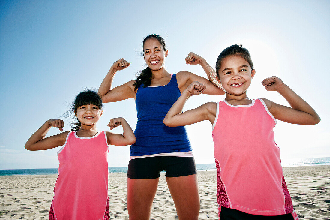 Mutter und Töchter beim Muskeltraining am Strand