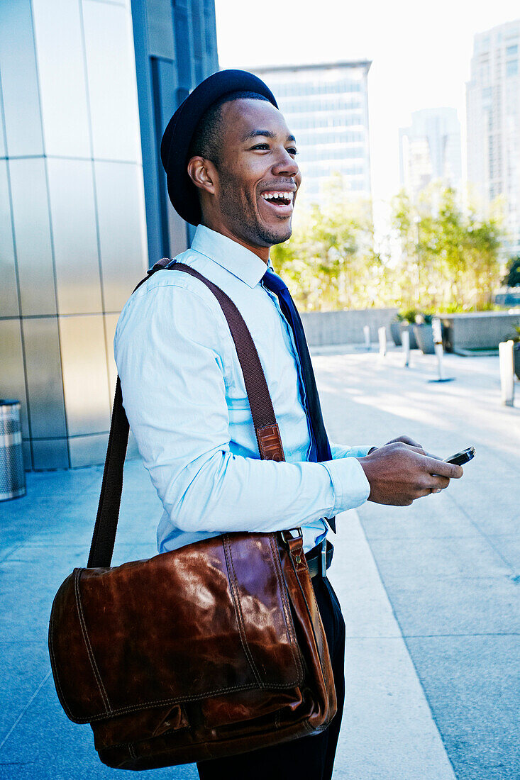 Black businessman using cell phone outside office building