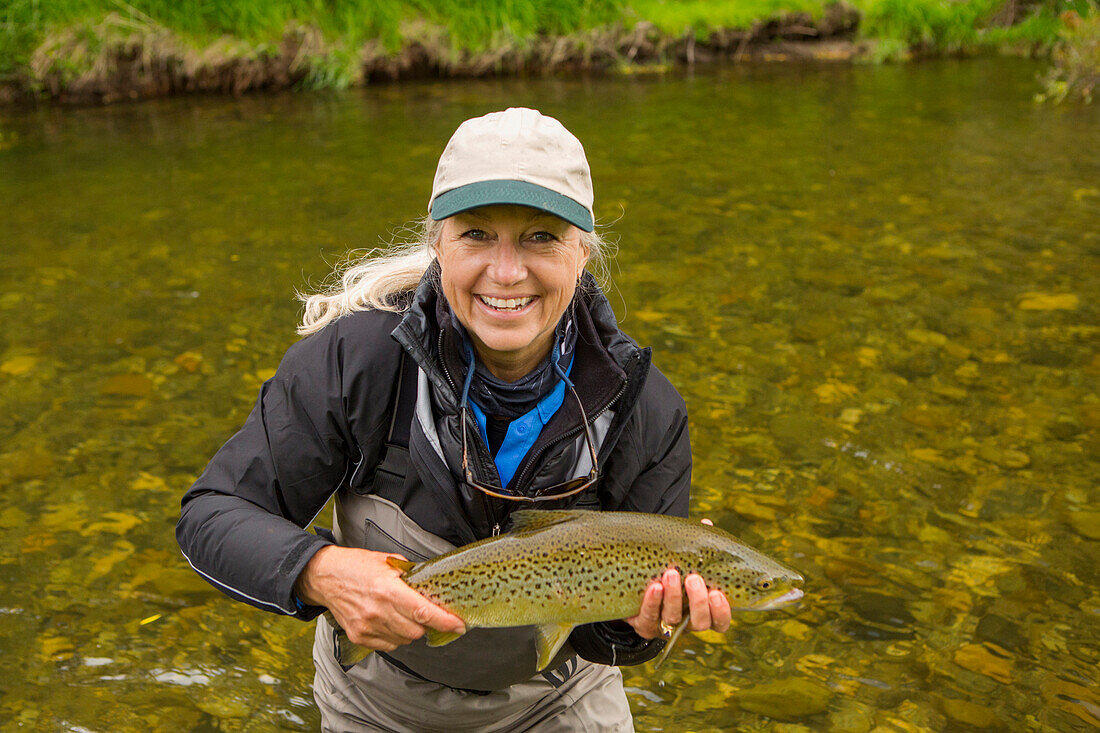 Caucasian woman holding fish in remote river