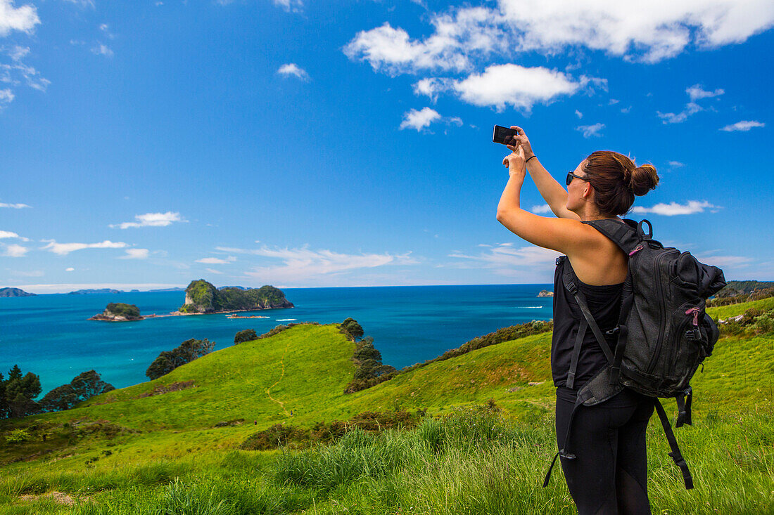 Caucasian hiker photographing cliff and seascape