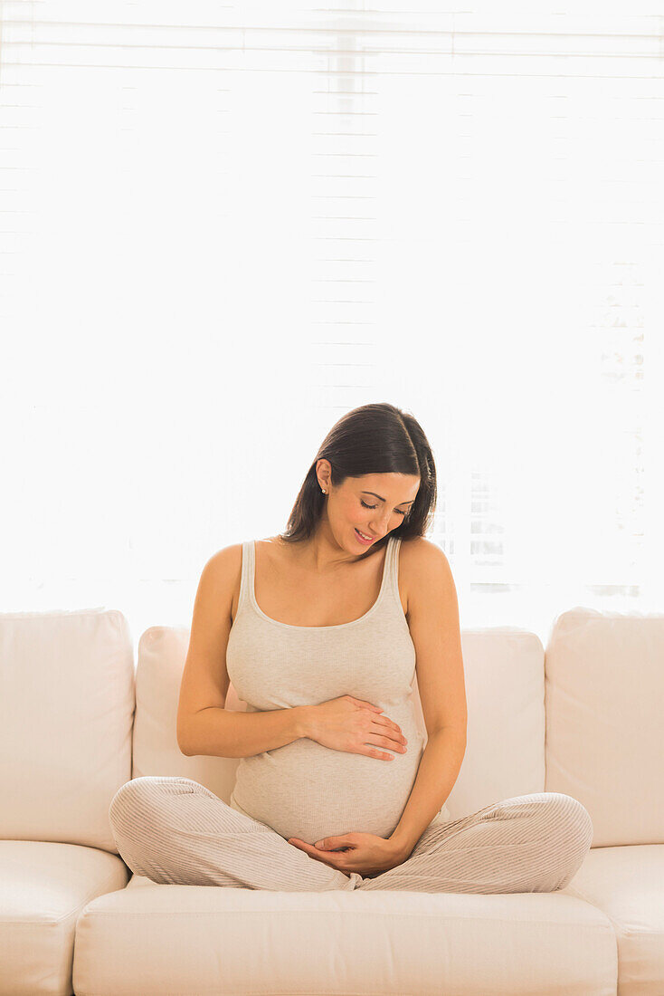 Pregnant Caucasian woman sitting on sofa