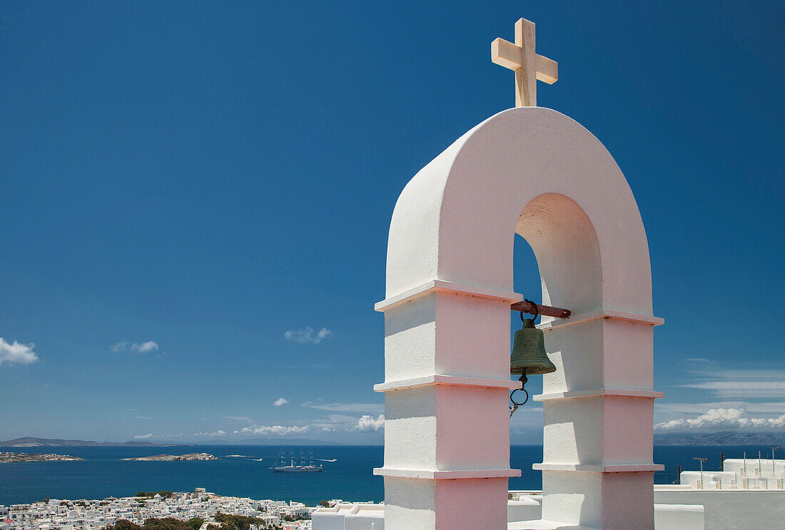 Bell arch and Mykonos cityscape under blue sky, Cyclades, Greece