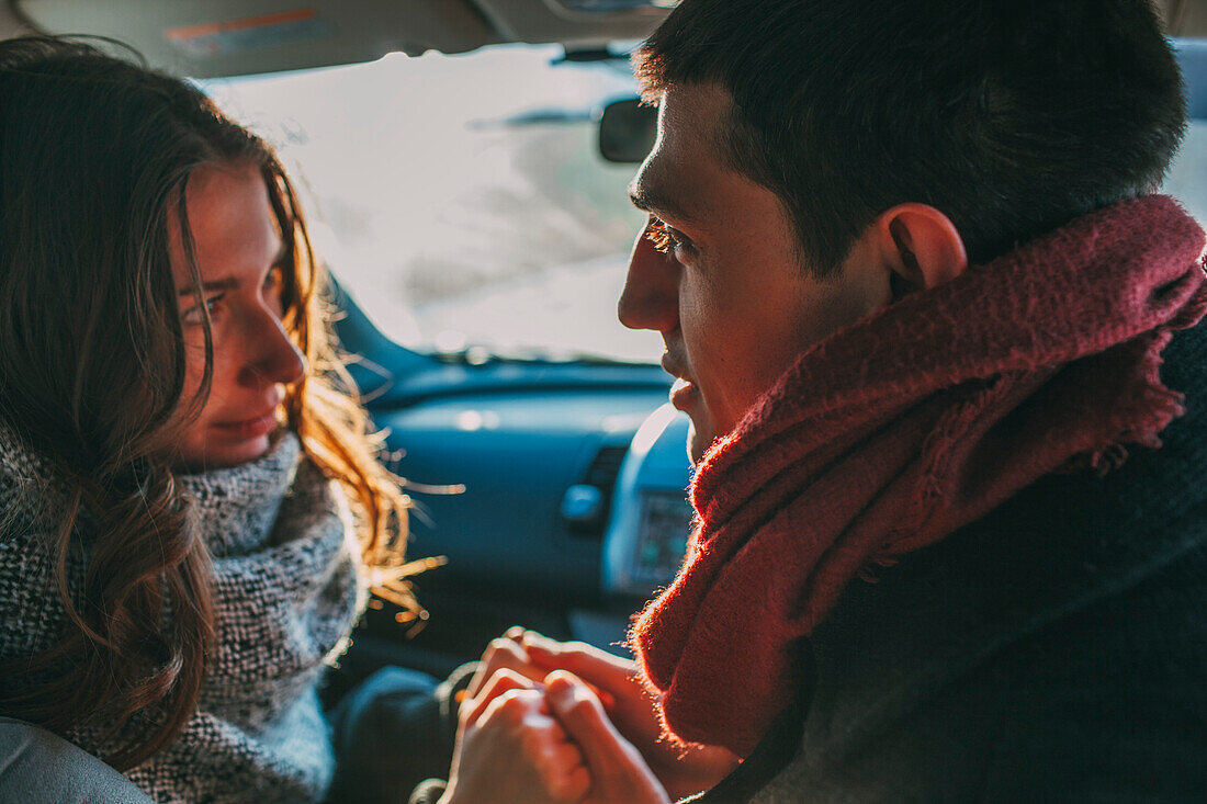 Young couple holding hands in car