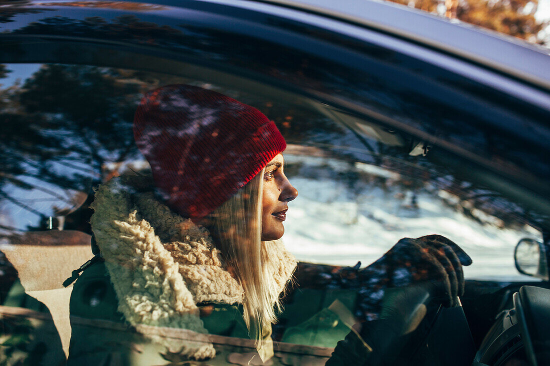 Woman in warm clothing driving car