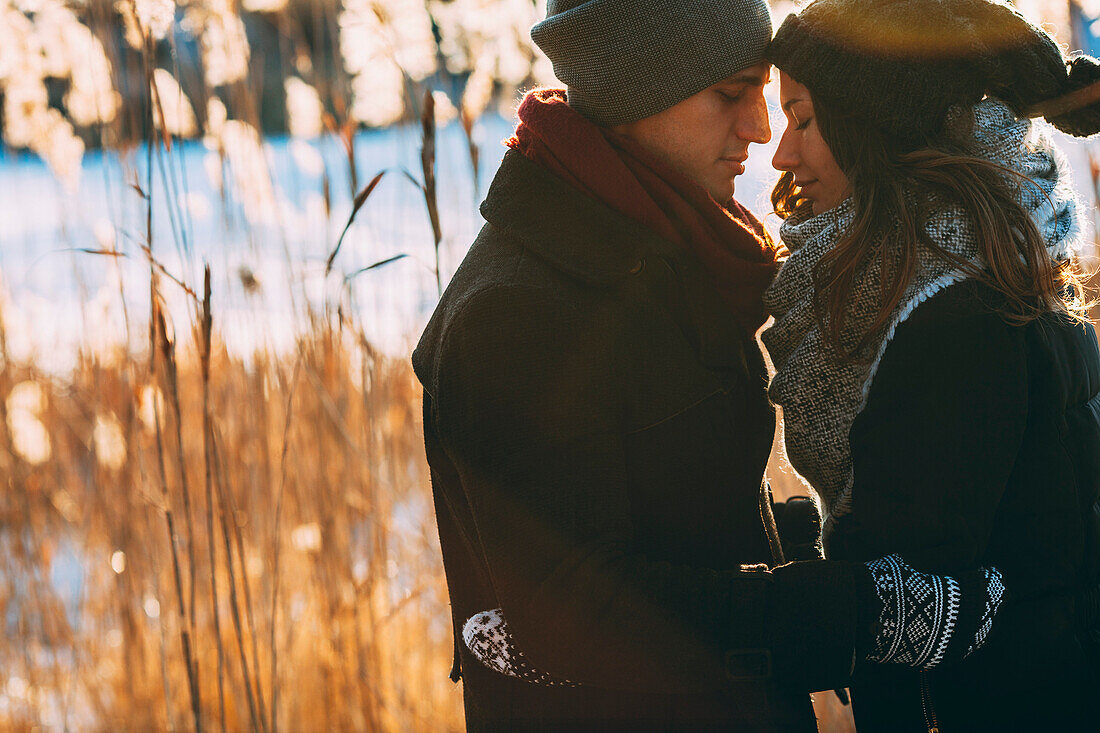 Young couple embracing while standing on field during winter