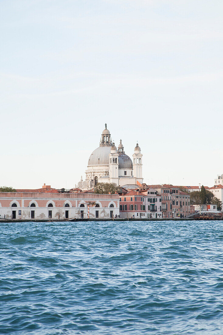 Santa Maria della Salute and buildings by canal against cleat sky
