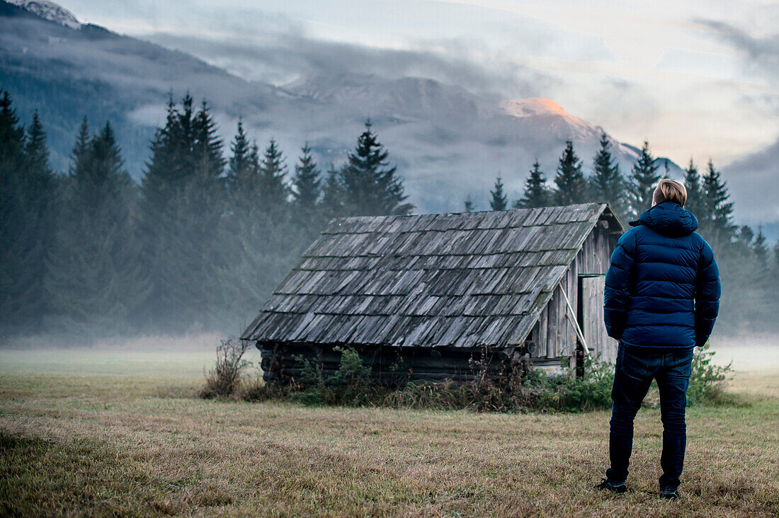 Man standing in front of a Hut between Ehrwald and Biberwier, Mieminger Range, Zugspitze, Alps, Fog, Tyrol, Austria