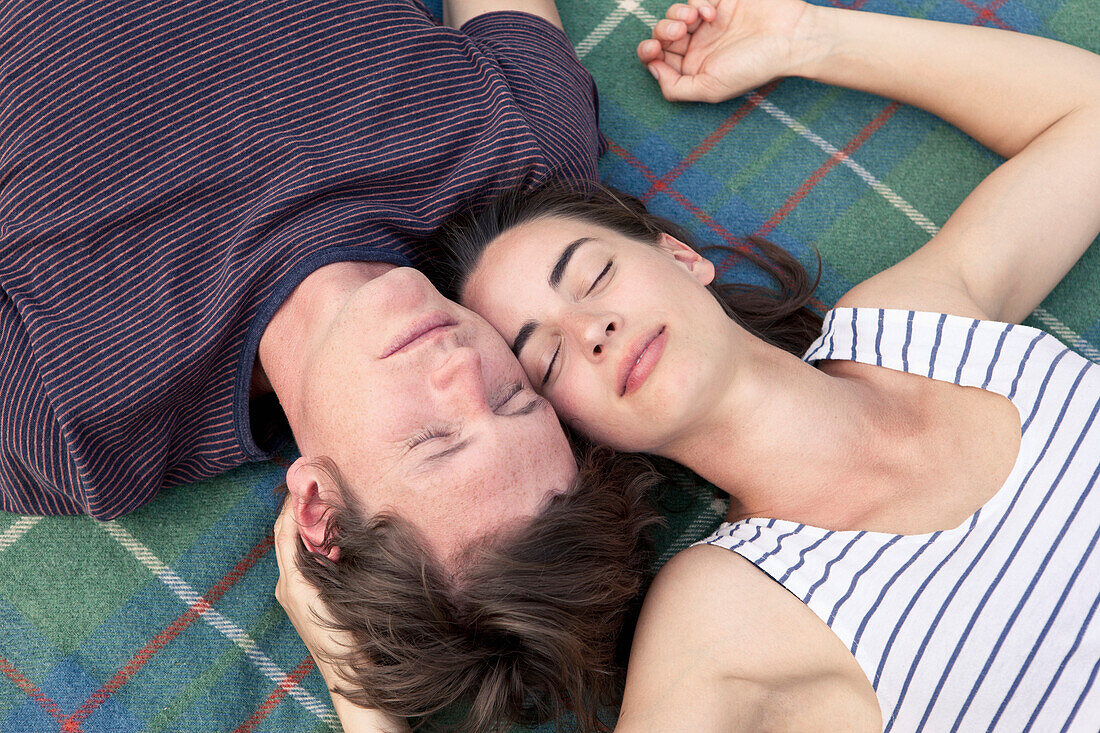 Young couple lying on picnic blanket, close-up