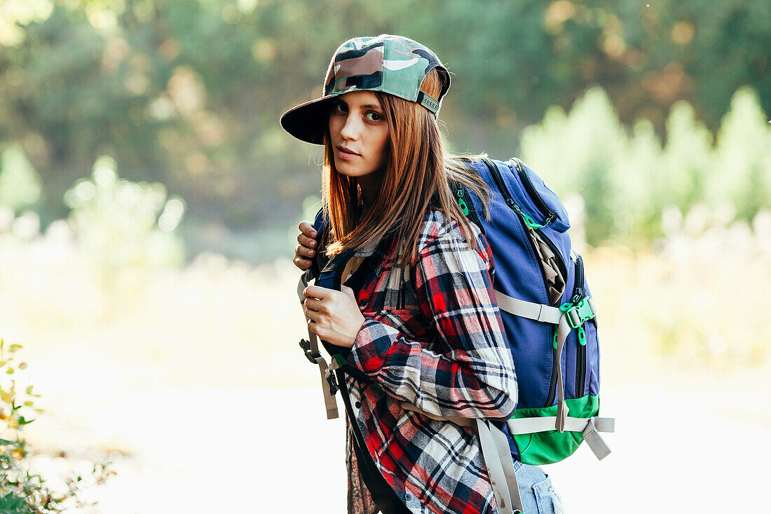Portrait of fashionable young woman hiking in forest