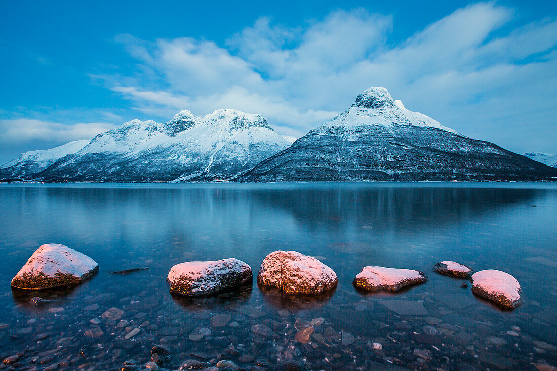 Blue sky at dusk and snowy peaks are reflected in the frozen sea, Storfjorden, Lapland, Lyngen Alps, Troms, Norway, Scandinavia, Europe