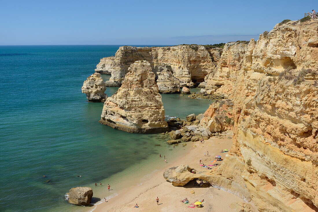 Overview of tourists on beach, sandstone cliffs and seastacks at Praia da Marinha, near Carvoeiro, Algarve, Portugal, Europe