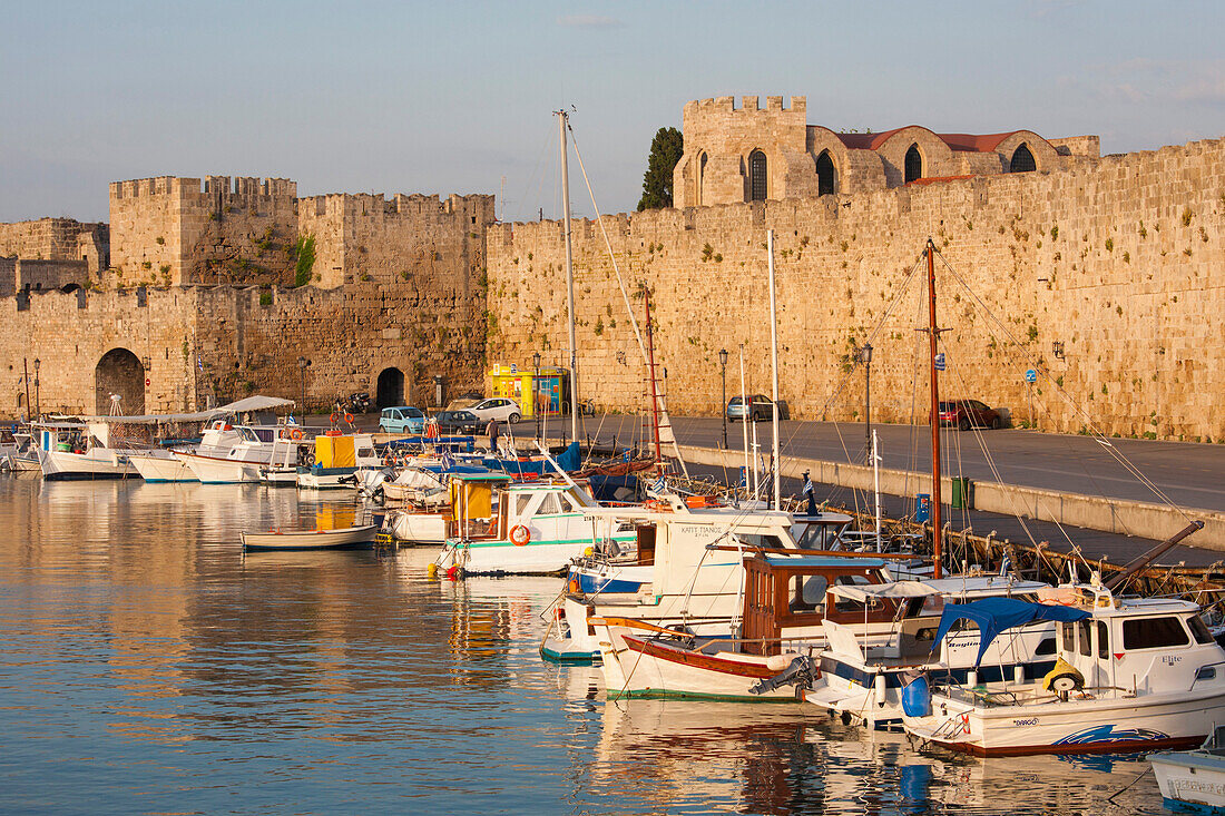 View across tranquil Kolona Harbour to the city walls, sunrise, Rhodes Town, Rhodes, Dodecanese Islands, South Aegean, Greece, Europe