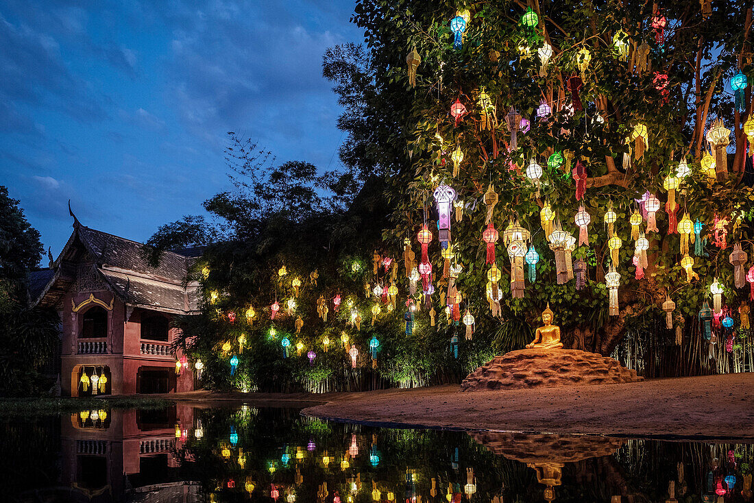 nächtliche Beleuchtung am See mit farbigen Lampions der heiligen Buddha Statue im Tempel Wat Phan Tao, Chiang Mai, Thailand, Südost Asien