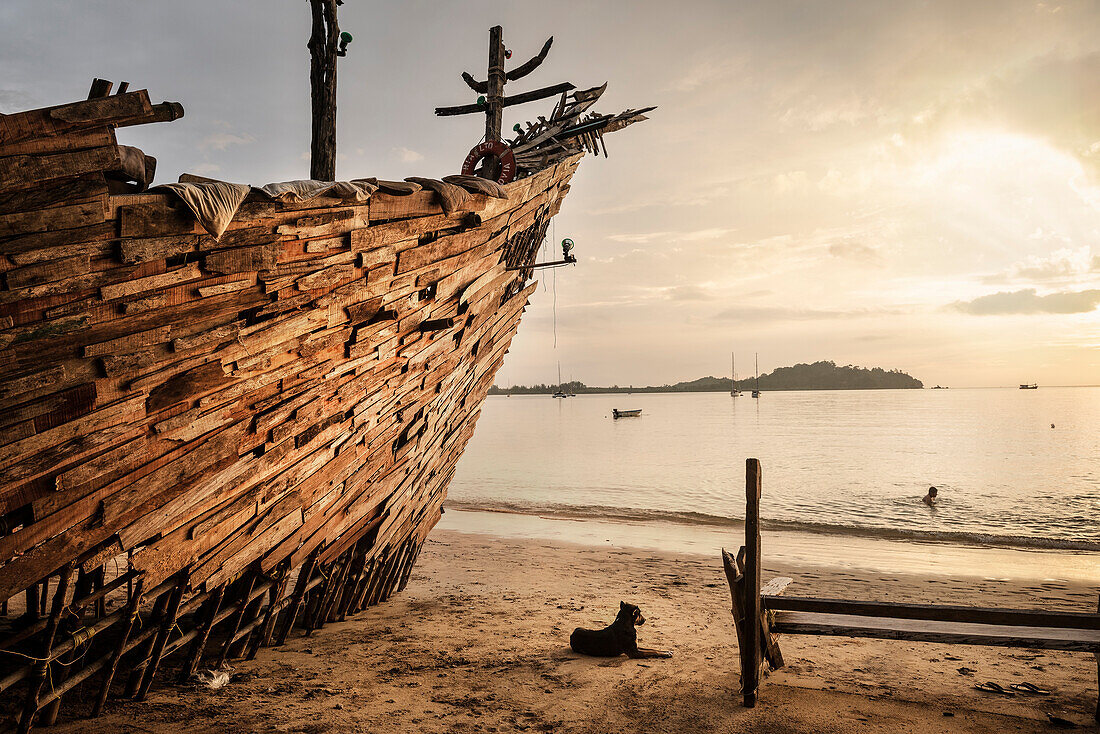 Hund genießt Sonnenuntergang neben der sog. Hippie Bar in Form eines Piratenschiffs in der Büffel Bucht Ao Khao Kwai, Ko Phayam, Andamanensee, Thailand, Südost Asien