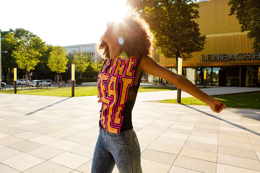 Young afro-american woman enjoying the sunshine at Lenbachplatz, Munich, Bavaria, Germany